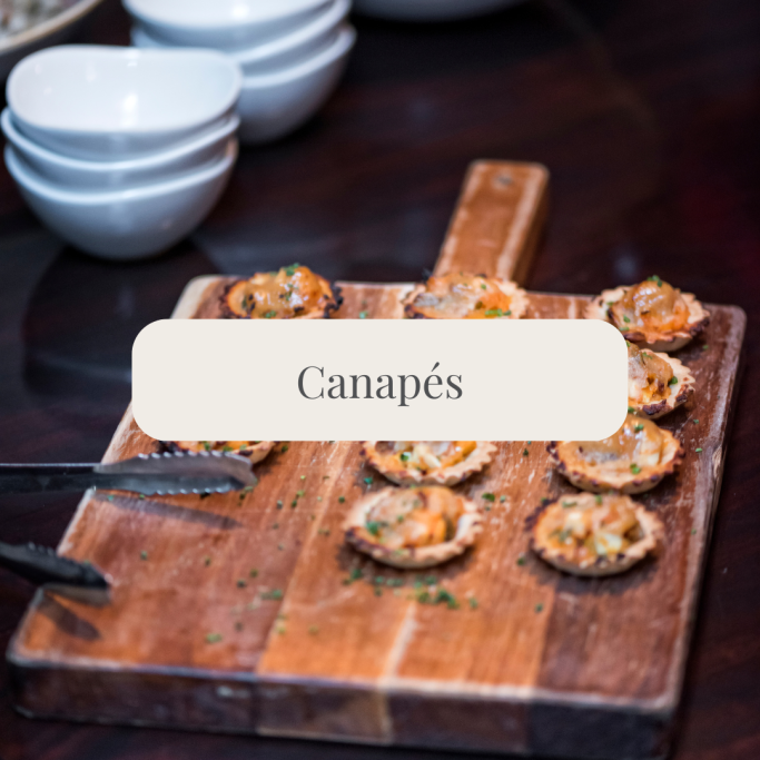 A wooden board with various canapés arranged on it.